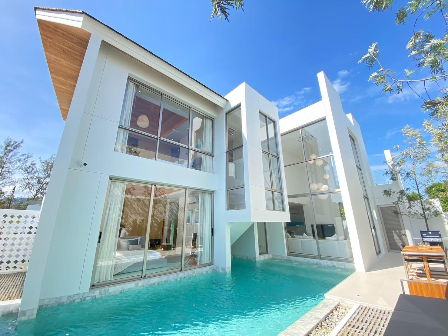 Modern Luxury Villa in Phuket with Private Pool and Floor-to-Ceiling Windows Modern Phuket villa with private pool, large glass windows, and white facade, used for luxury rental and villa management marketing.